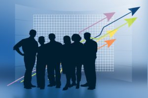 business people standing in the dark, with colored arrows going upward behind them